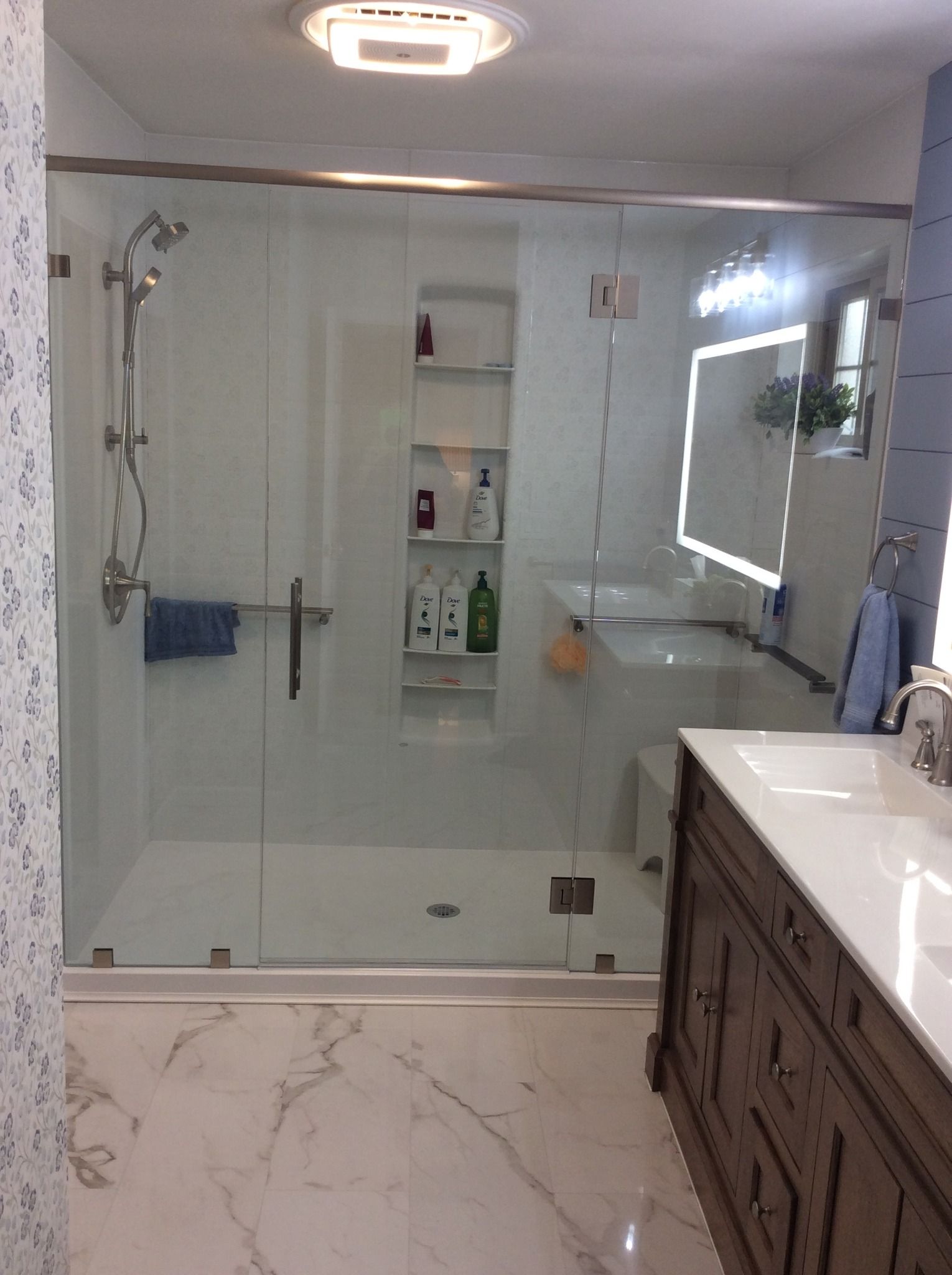 A bathroom with a walk in shower , sink and mirror.