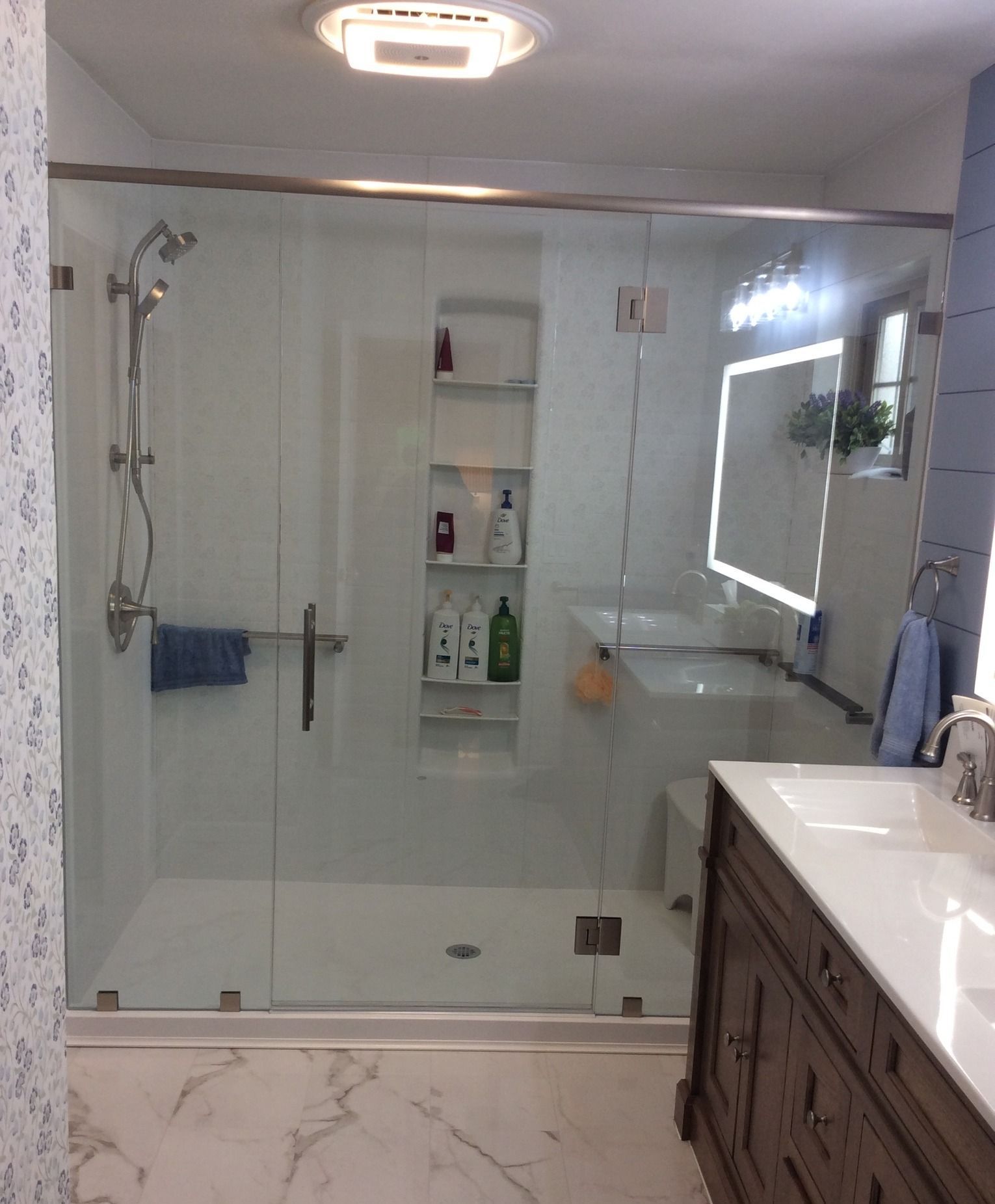 A bathroom with a glass shower door and a sink