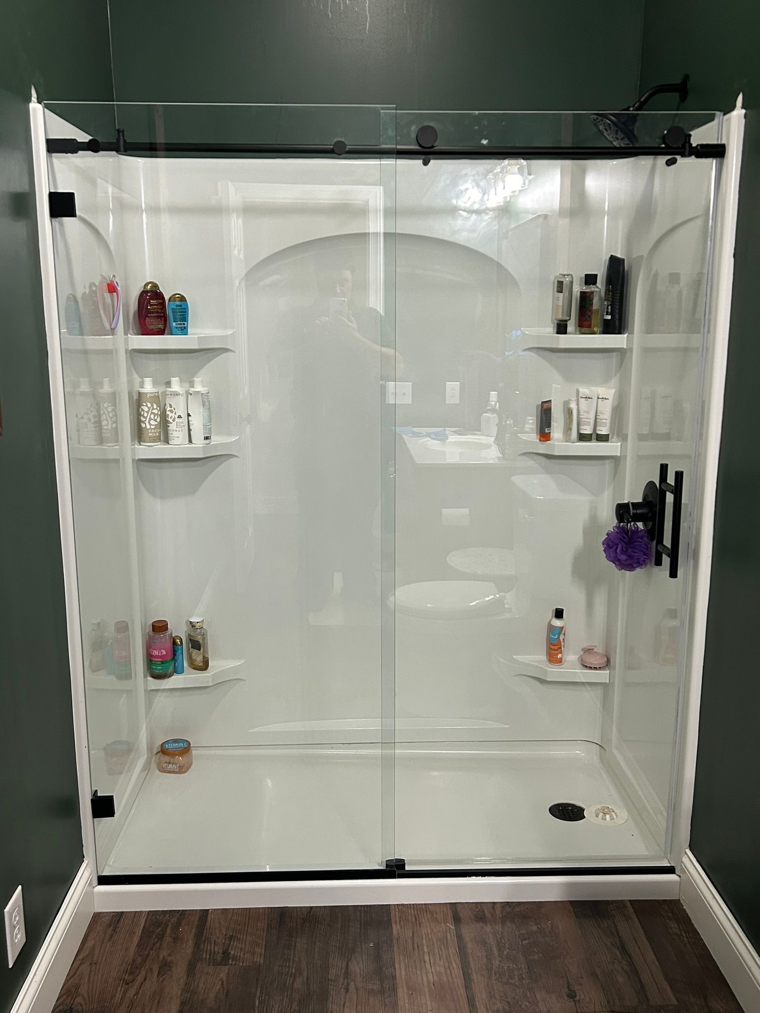A shower stall with sliding glass doors and shelves in a bathroom.