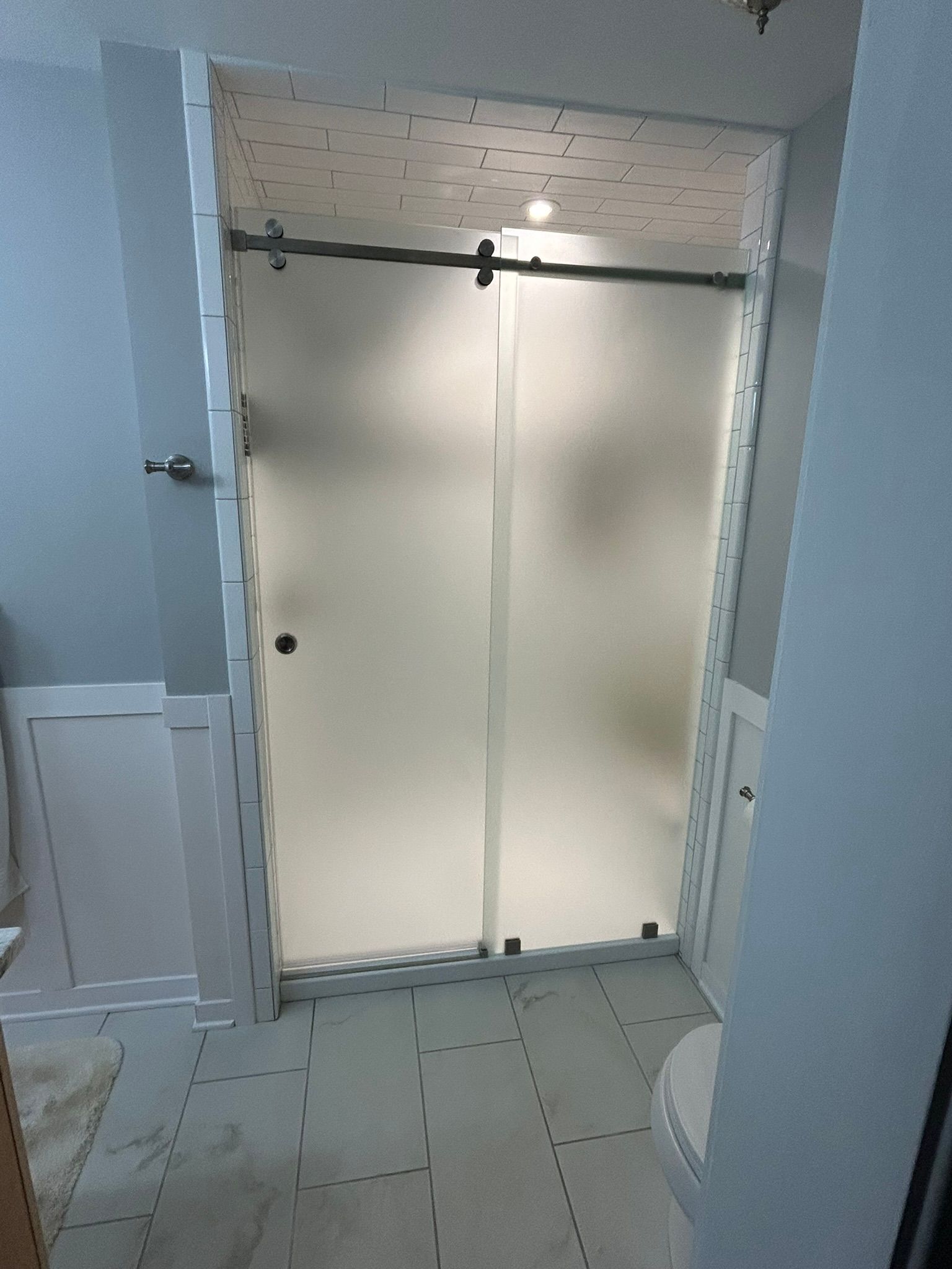 A bathroom with a sliding glass shower door and a toilet.