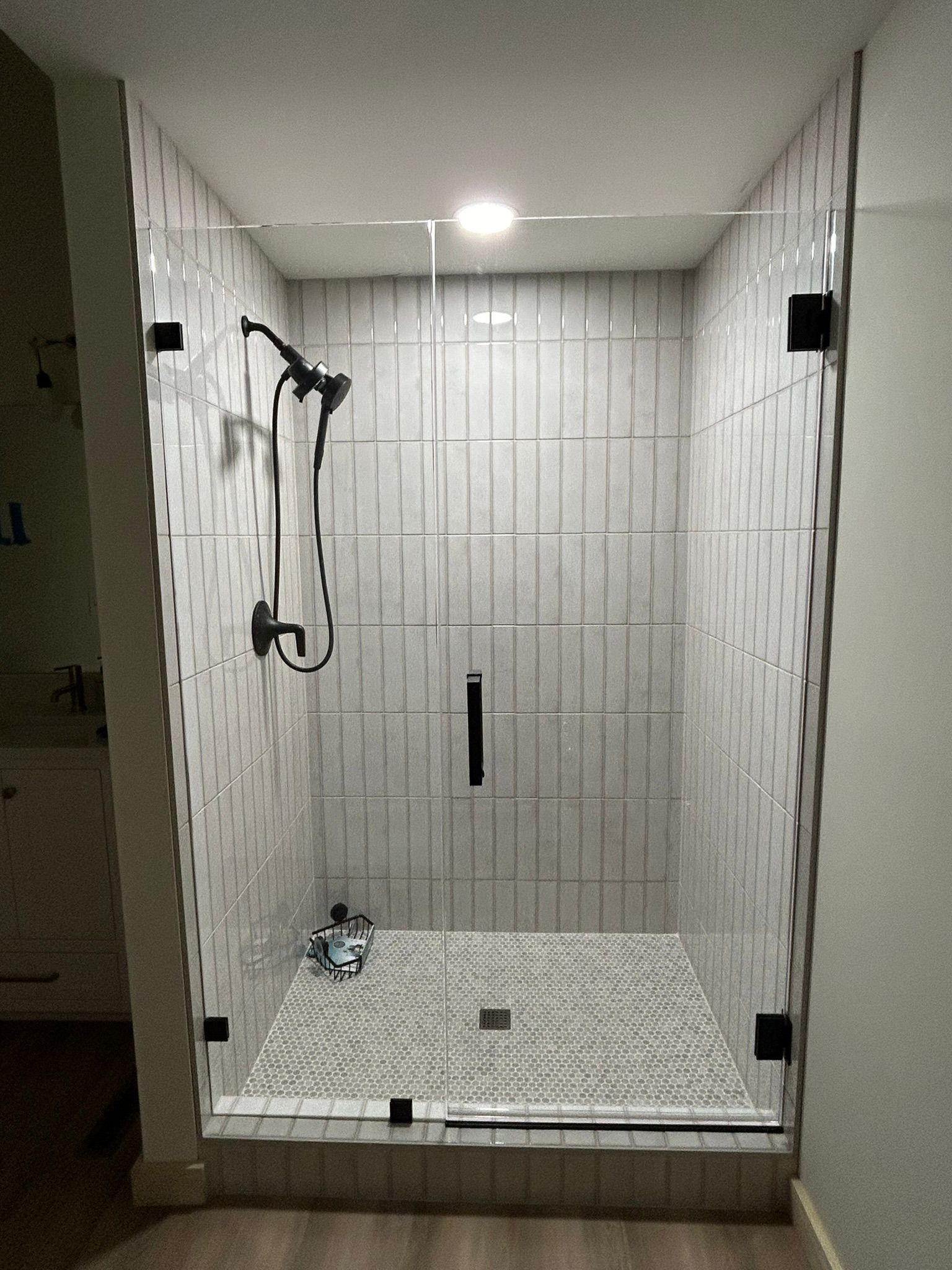 A shower stall with a glass door and a shower head in a bathroom.
