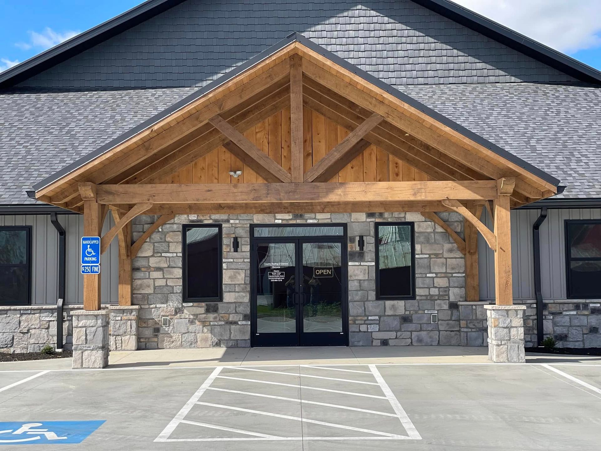 Building entrance with wooden awning, stone facade, glass doors, and accessible parking.