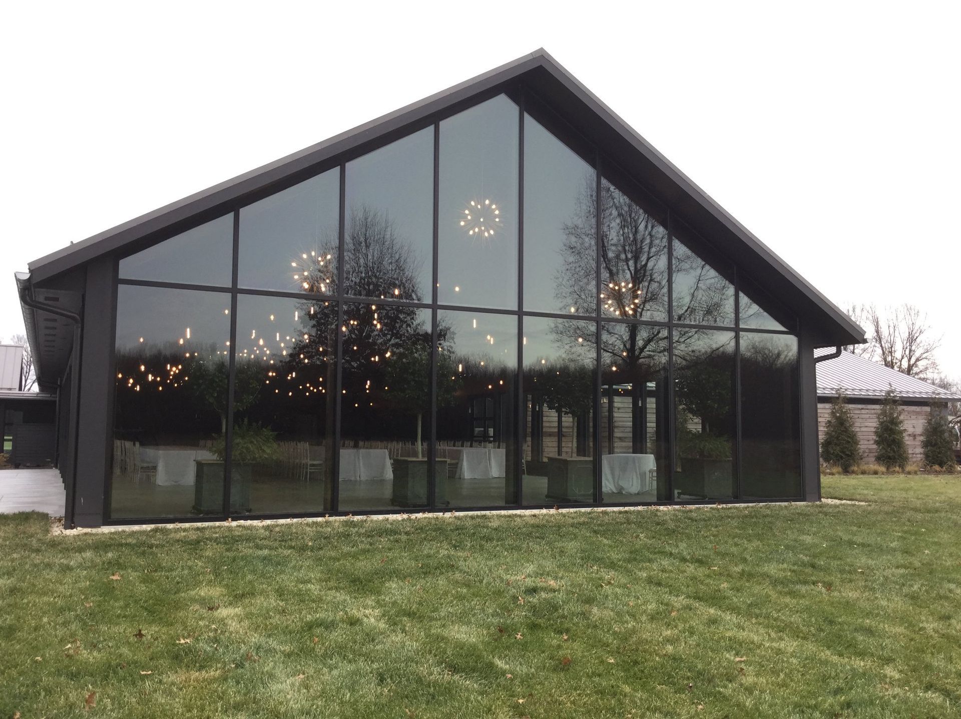 A black building with a triangle shaped roof is sitting on top of a grassy hill.