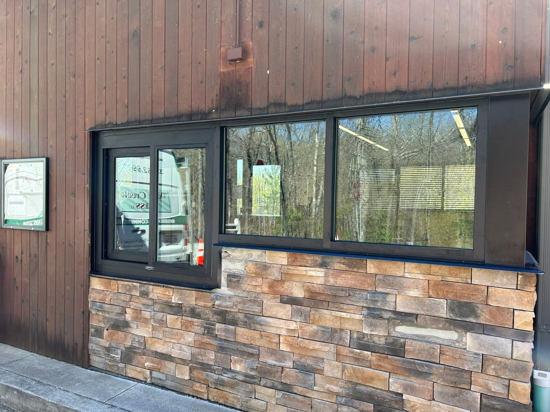 A building with brown wood siding, stone base, and windows.