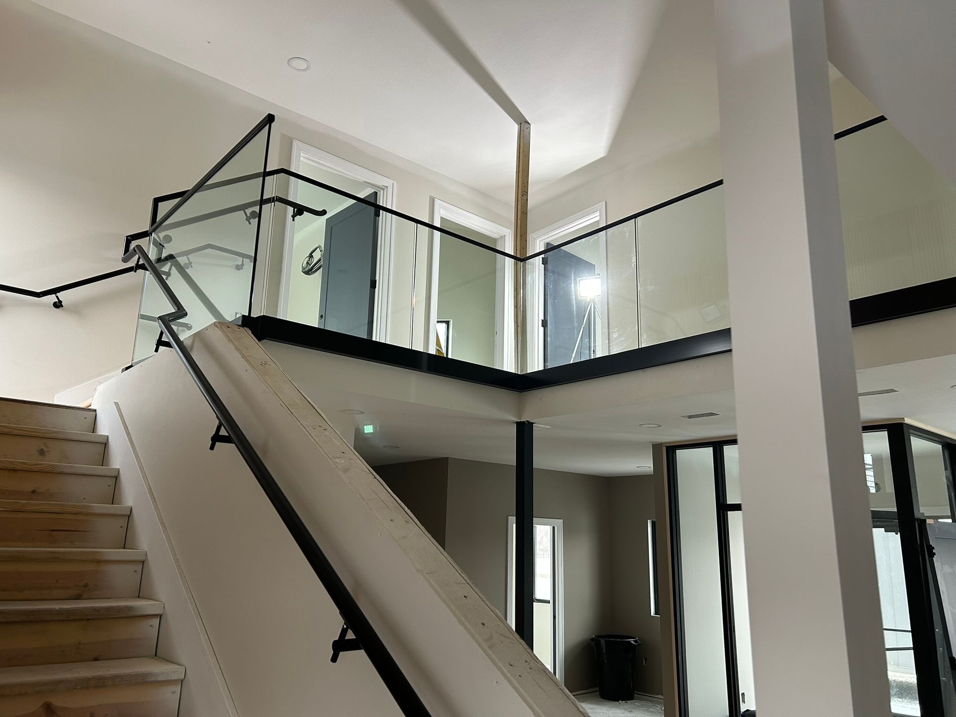 Interior view of a modern building with a staircase and a mezzanine featuring glass railings.