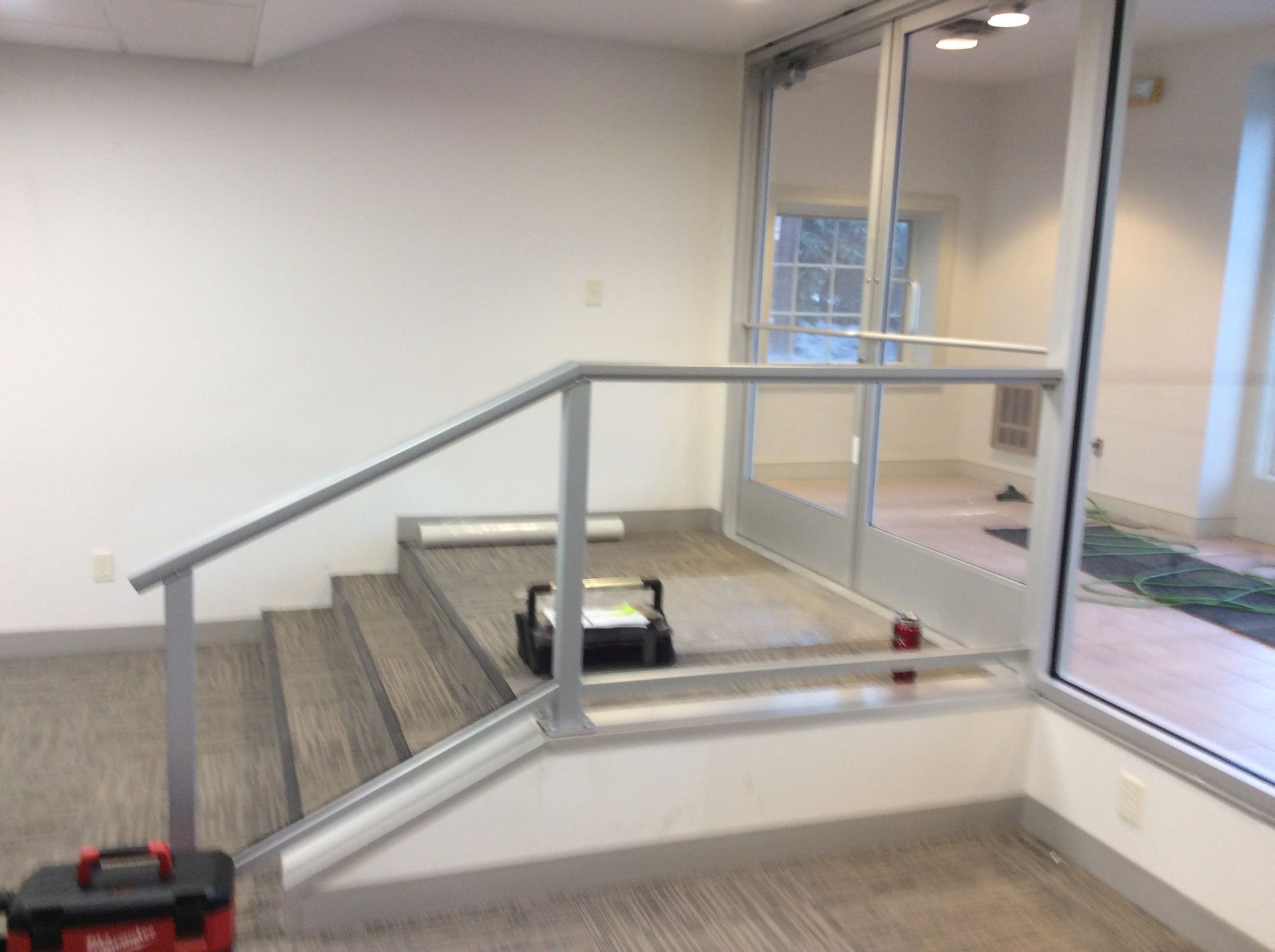 Interior with short staircase, metal handrail, glass doors. Tool box on floor.