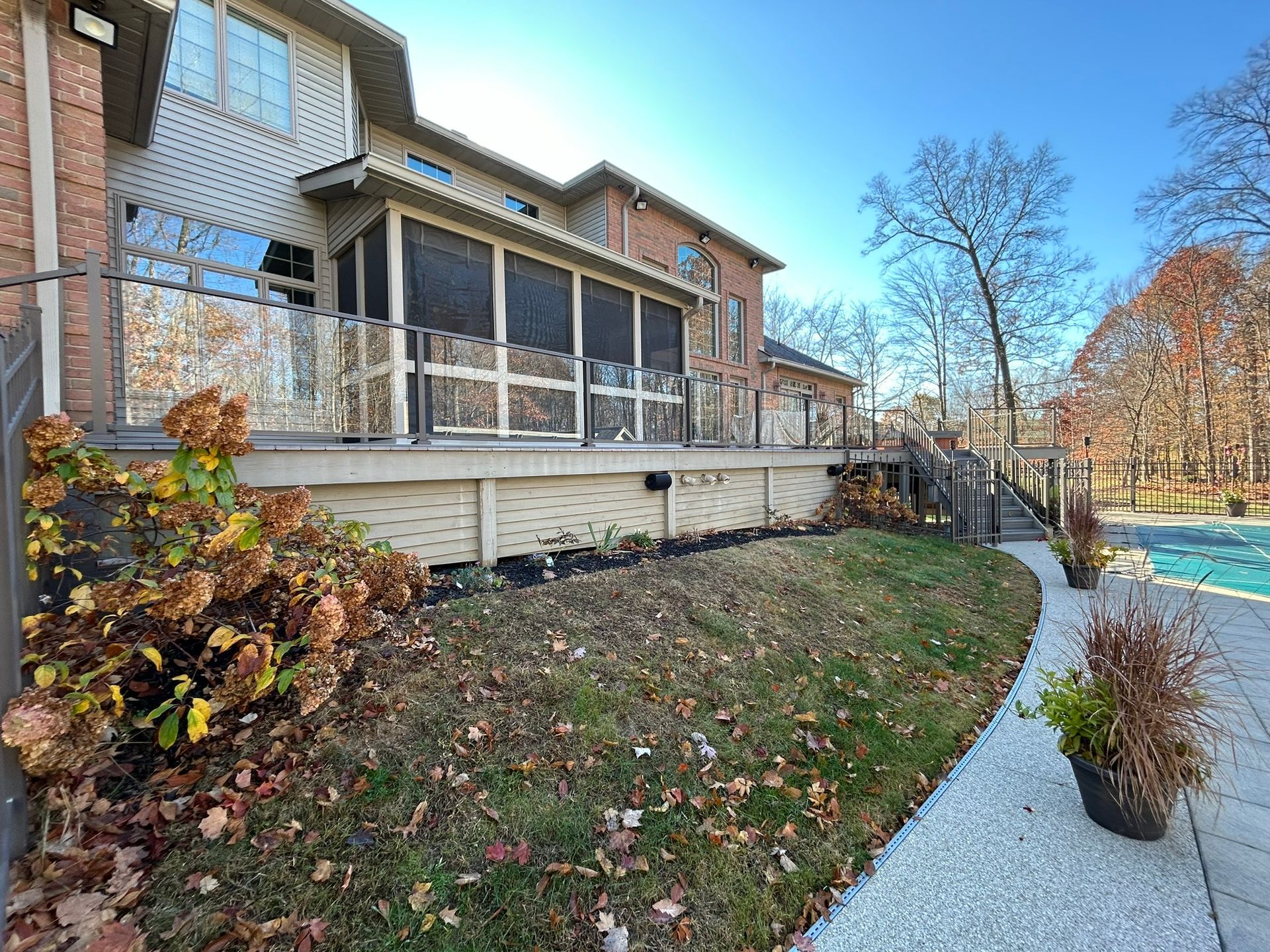 A house with a screened porch and deck overlooking a backyard with a pool.