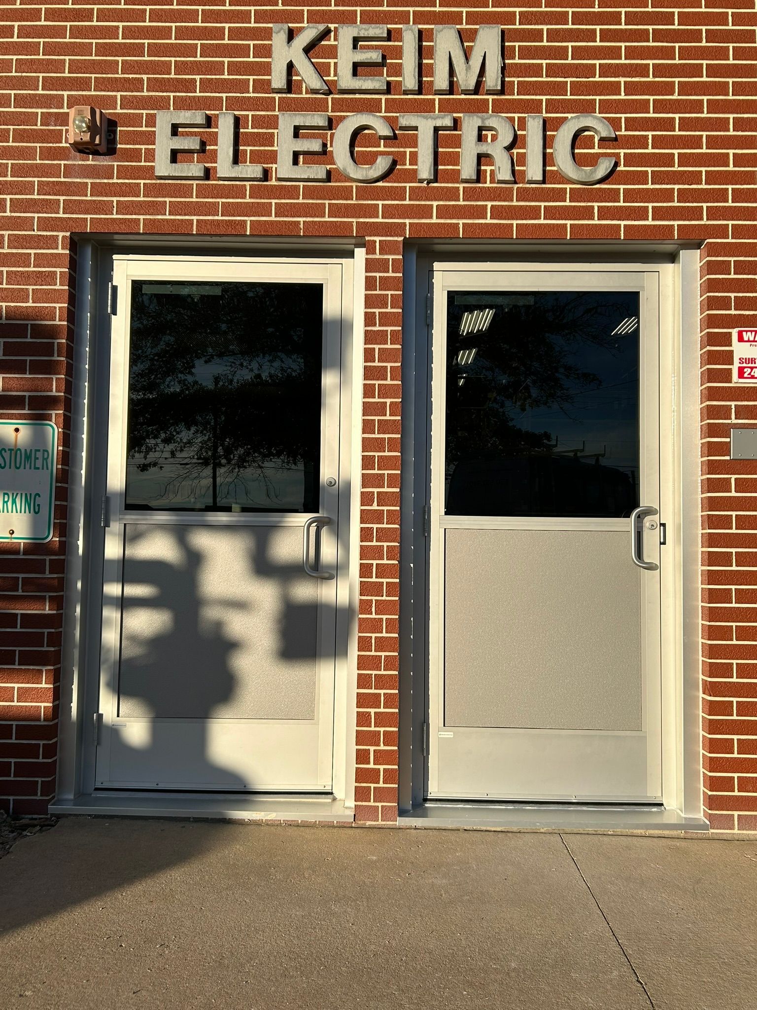 Two white doors with frosted glass panels at Keim Electric building.