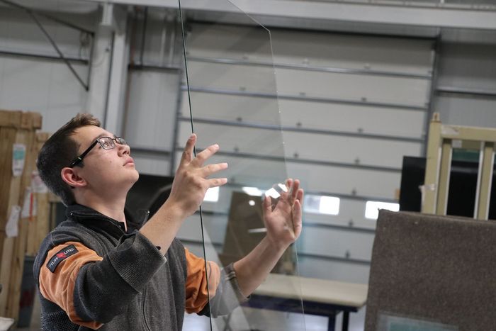 A man is working on a piece of glass in a factory.