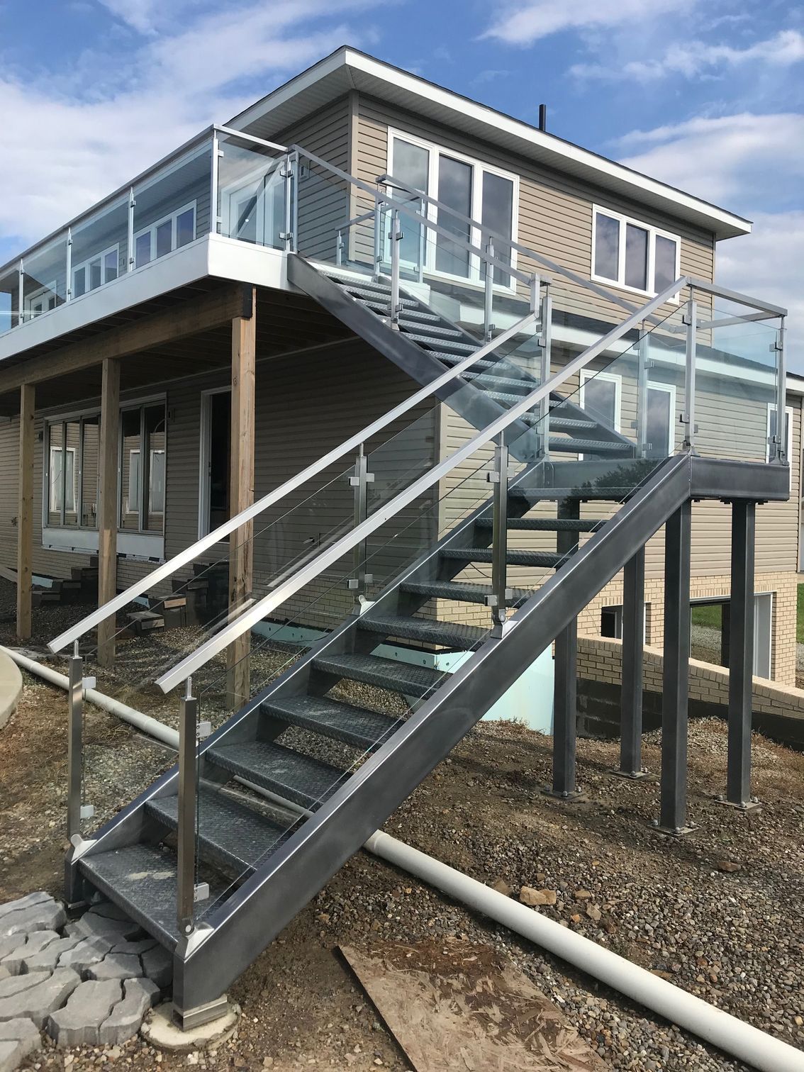 A set of stairs leading up to a house with a glass railing.