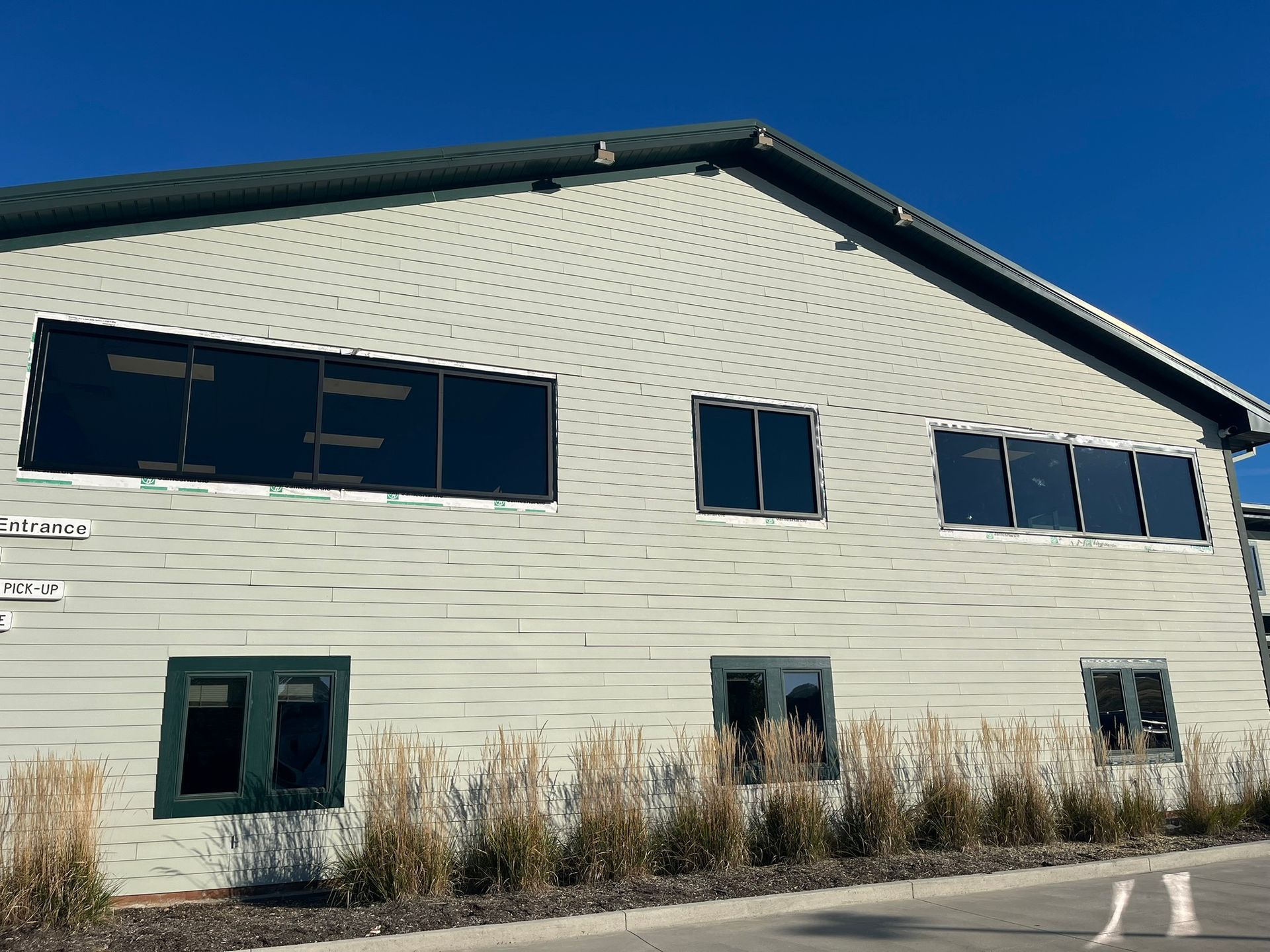 Exterior of a two-story building with dark-tinted windows, green trim, and light green siding.