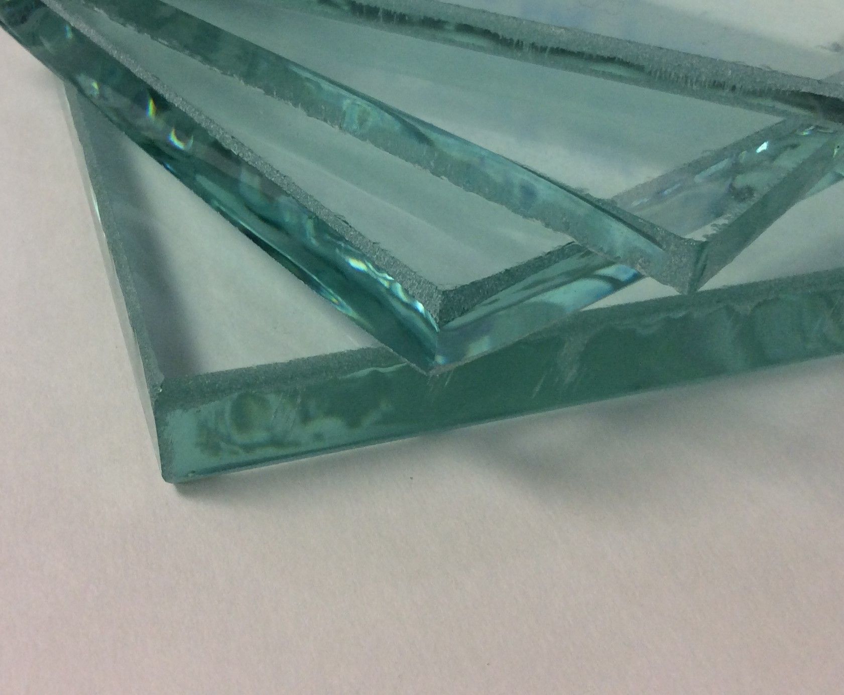 Three pieces of clear glass are stacked on top of each other on a white surface.