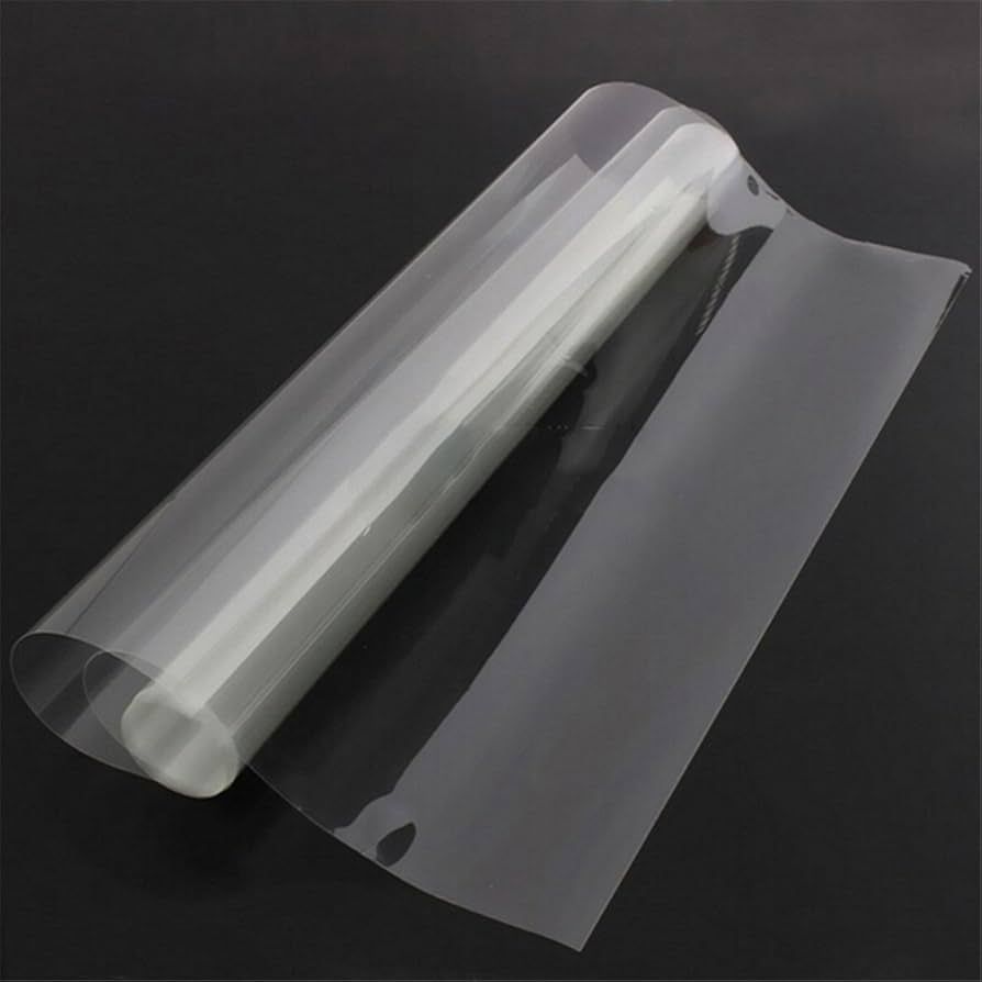 A roll of clear plastic wrap is sitting on a black surface.