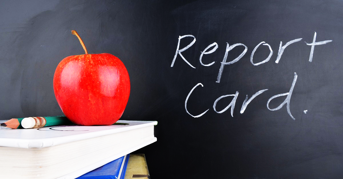 An apple sits on top of a book in front of a blackboard that says report card