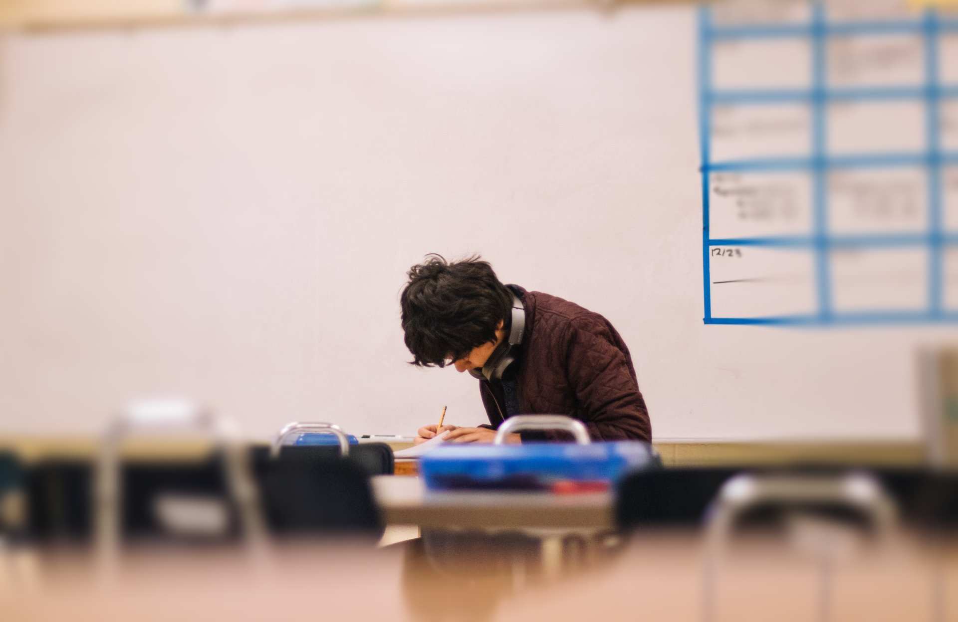 A man is sitting at a desk in a classroom.