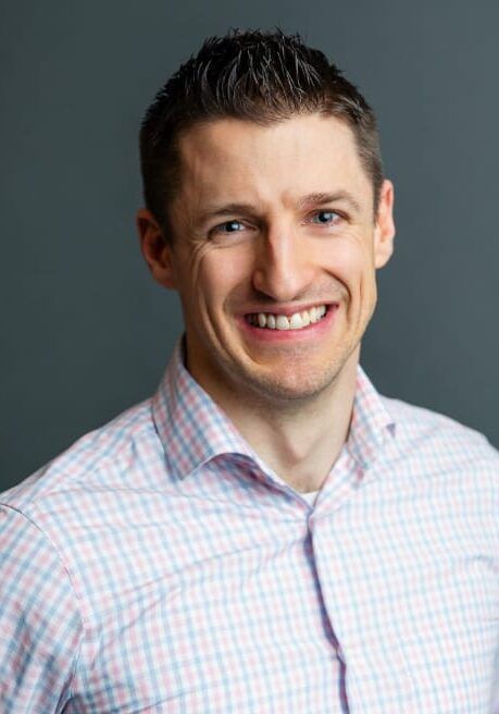 Smiling man in a light checkered shirt against a gray background