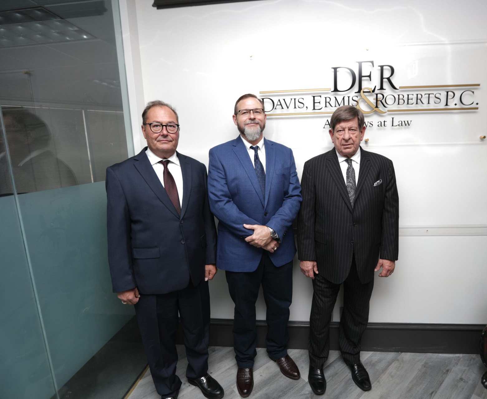 Three men in suits and ties are standing in front of a sign that says der