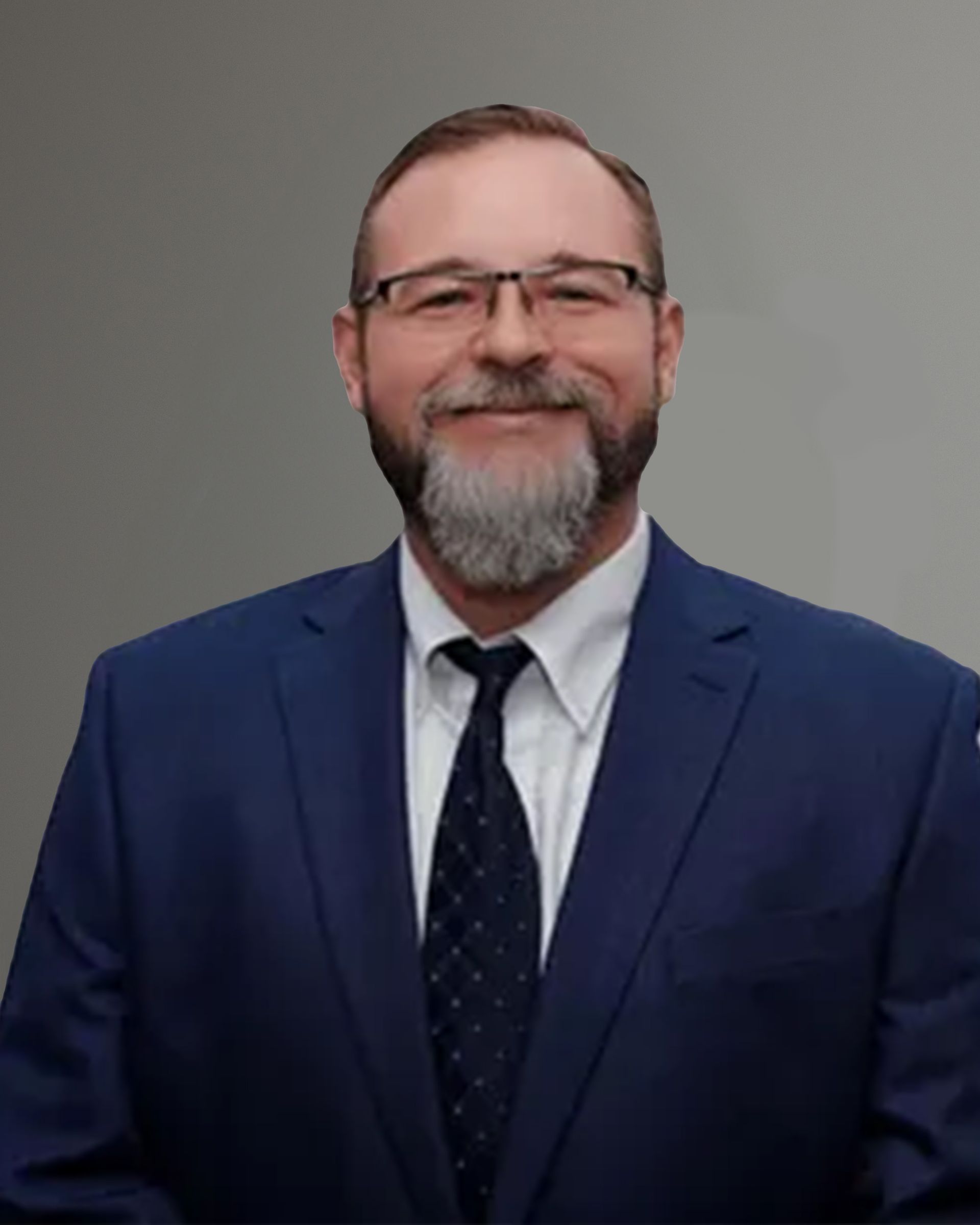 A man with a beard and glasses is wearing a blue suit and tie.
