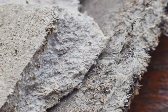 Close-up of rough, gray stone or concrete texture with layered cracks and debris