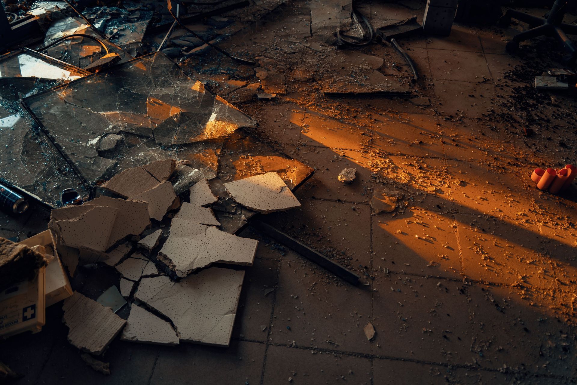 Broken floor tiles with debris and an orange streak of light across a dark surface