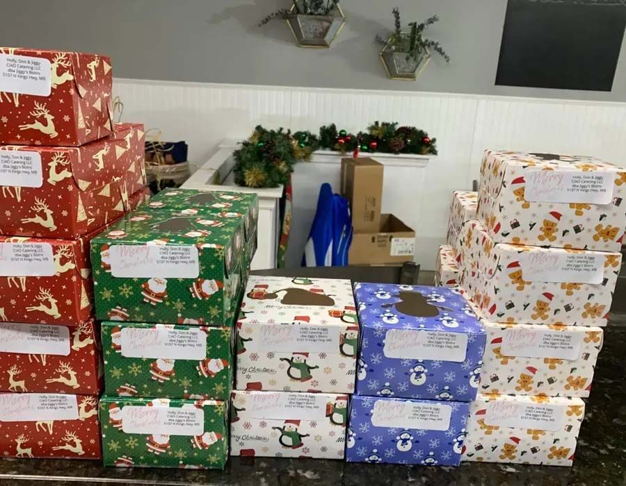 A collection of neatly wrapped Christmas gifts with handwritten address labels sitting on a dark countertop.