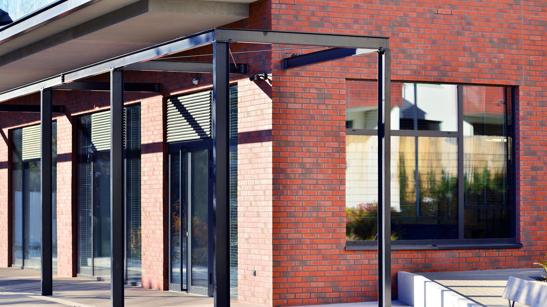 Commercial building entrance with brick walls, metal canopy supports, and glass windows. Commercial building entrance with brick walls, metal canopy supports, and glass windows.
