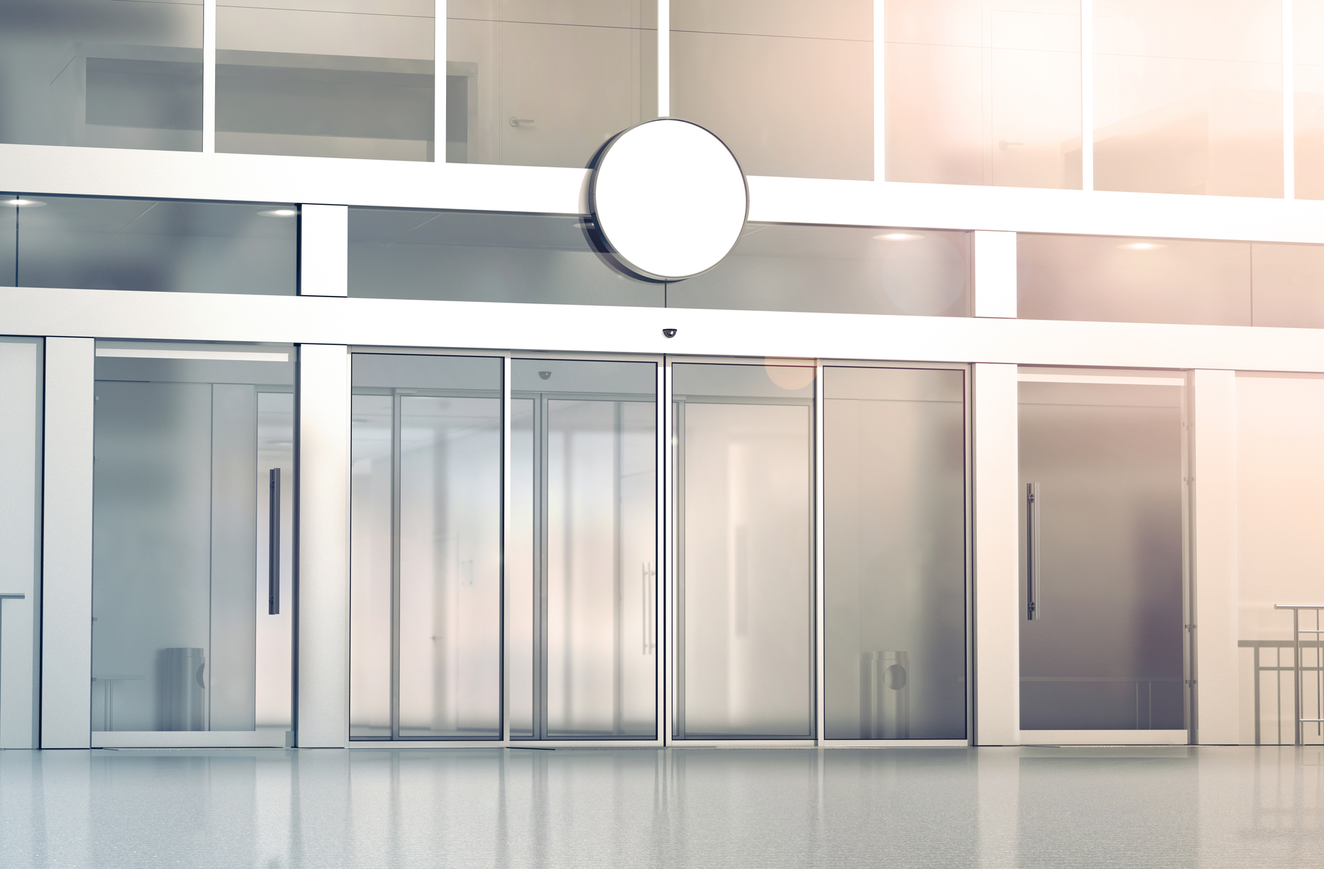 Modern glass commercial building entrance with sliding doors and clean reflective interior zone area.