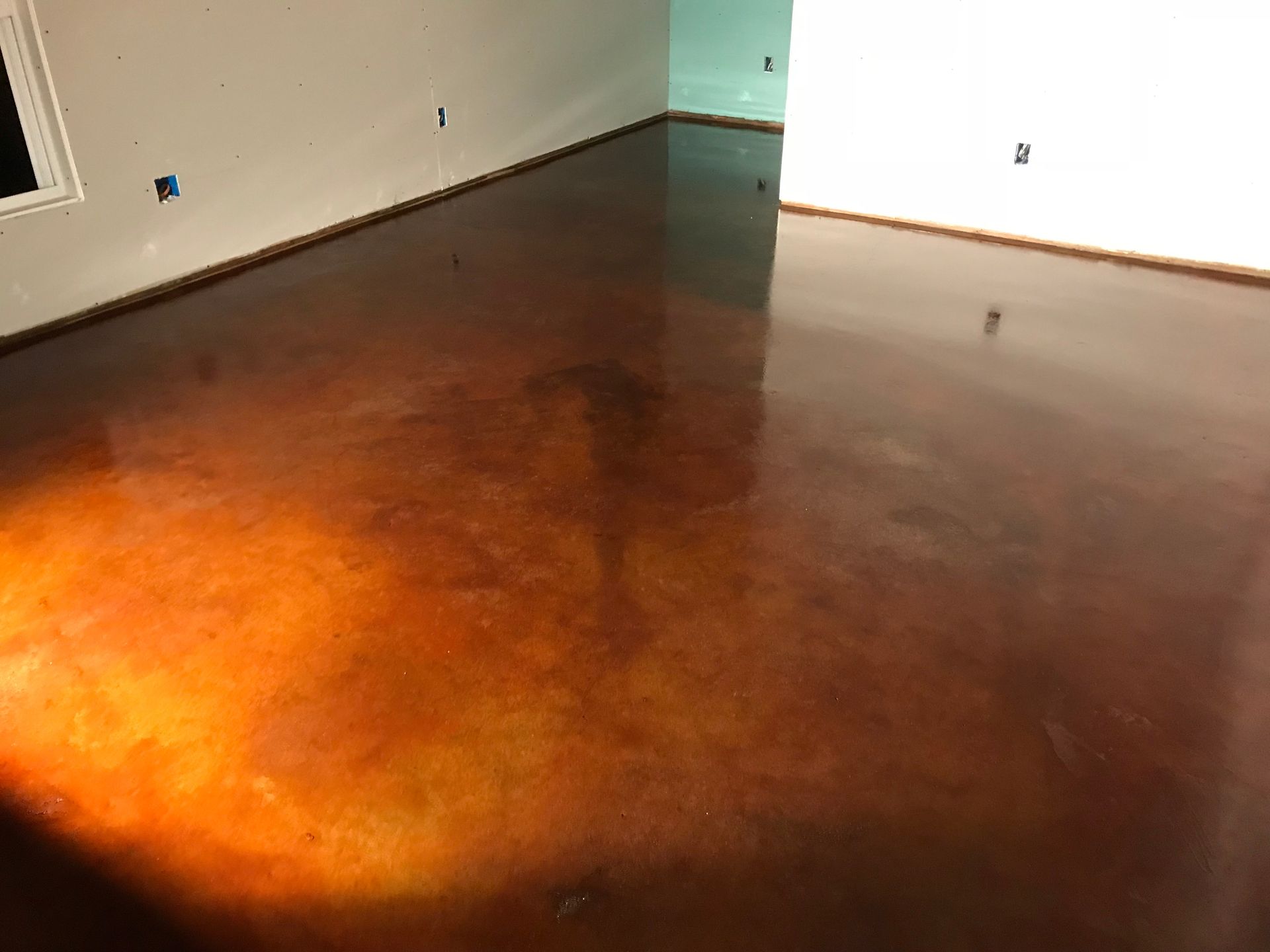 A room with a brown concrete floor and white walls.