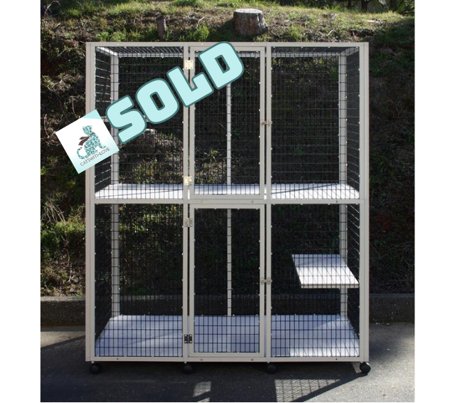 White wire cat enclosure with shelves, three compartments, and wheels, outdoors.