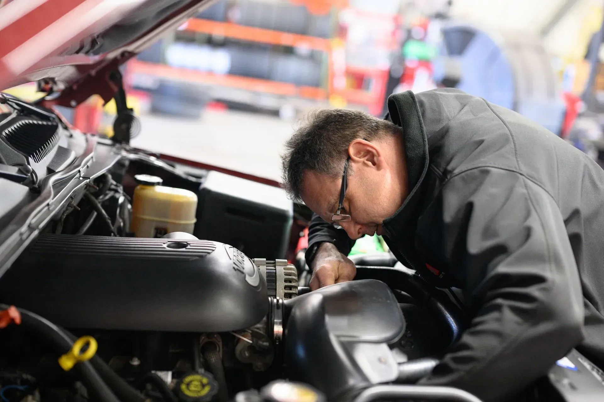 Mechanic inspecting car engine in a repair shop.