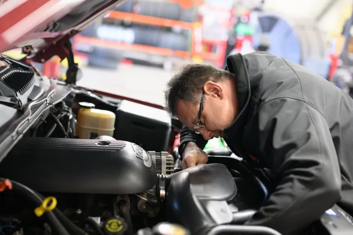 Mechanic inspecting car engine in a repair shop.