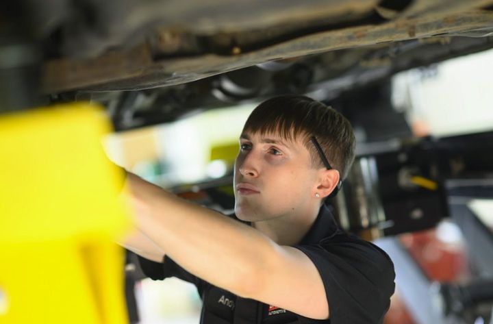 Mechanic inspecting car engine in a repair shop.