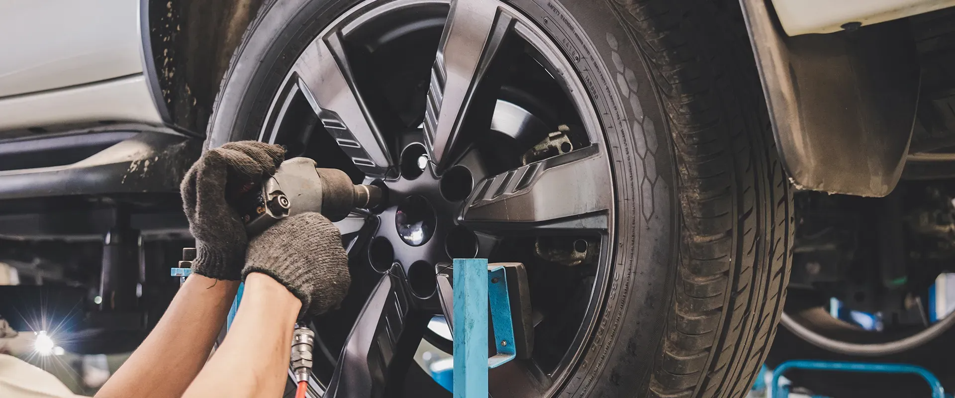 Mechanic using a power tool to remove a car tire.