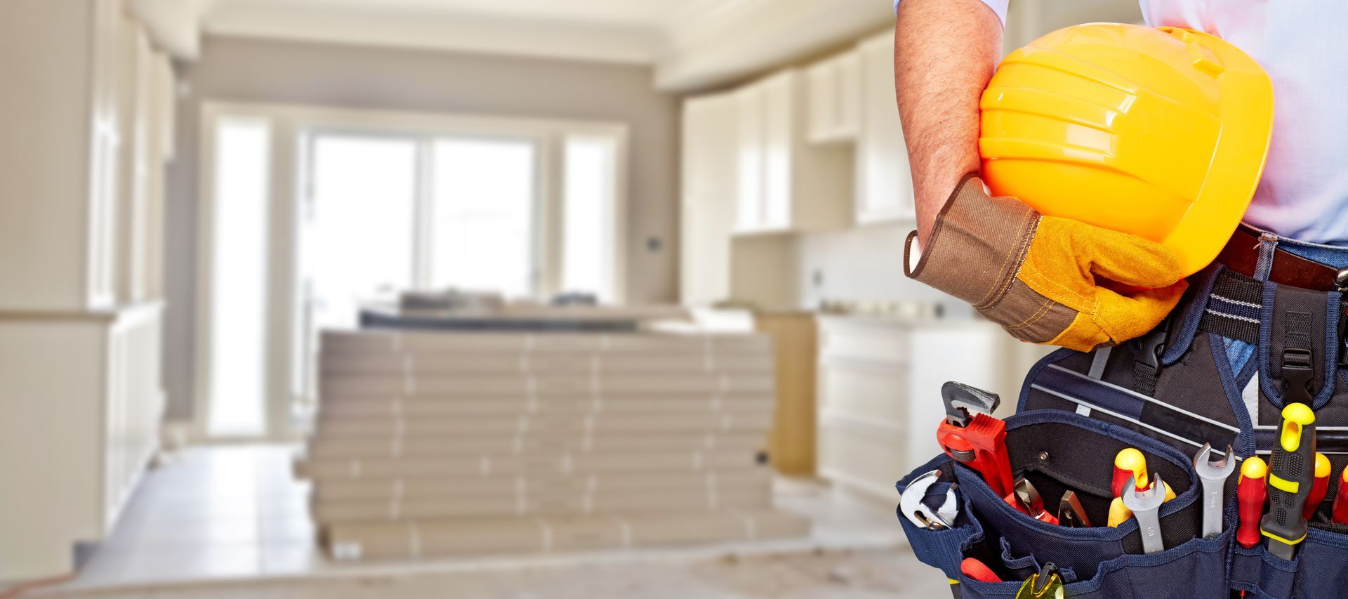 Construction worker with yellow hard hat in unfinished room with stairs and bright windows