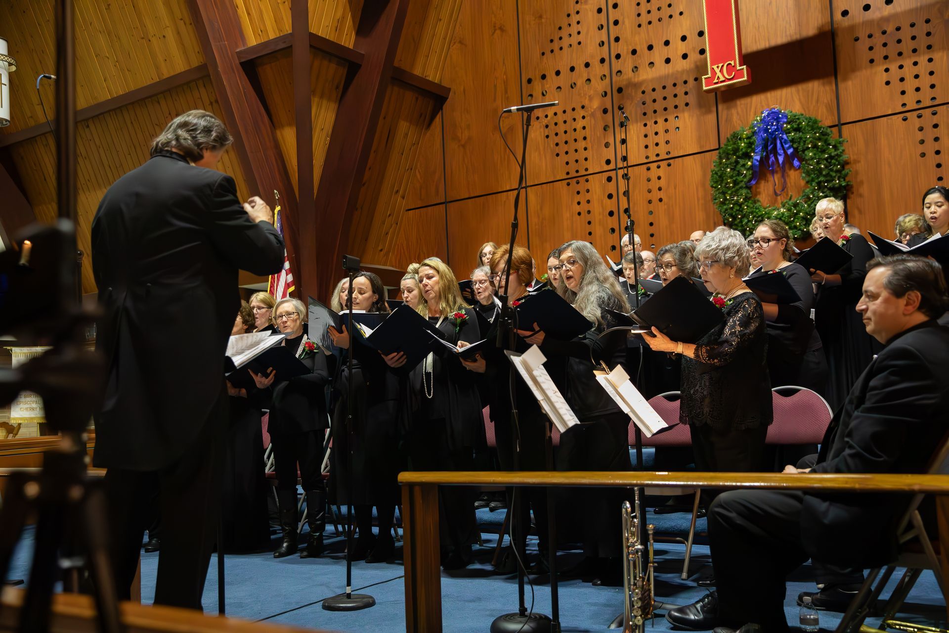 a group of men in tuxedos are singing in a choir