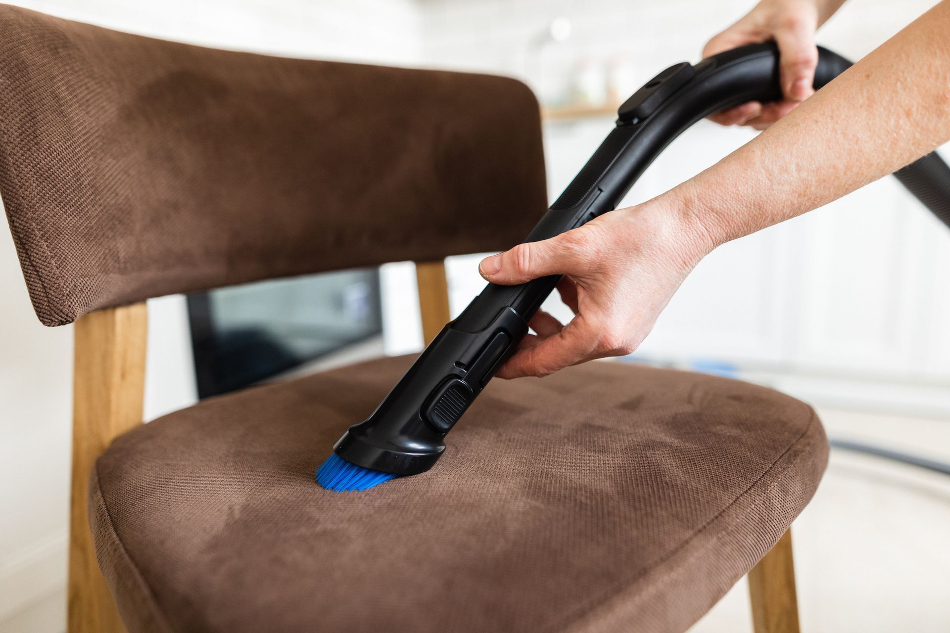 Close-up view of vacuuming the chair using an upholstery brush - Ottumwa, IA - Heaven's Best Ottumwa, IA
