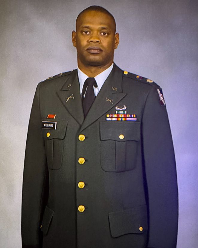 Man in military uniform, standing, looking forward. Formal setting.