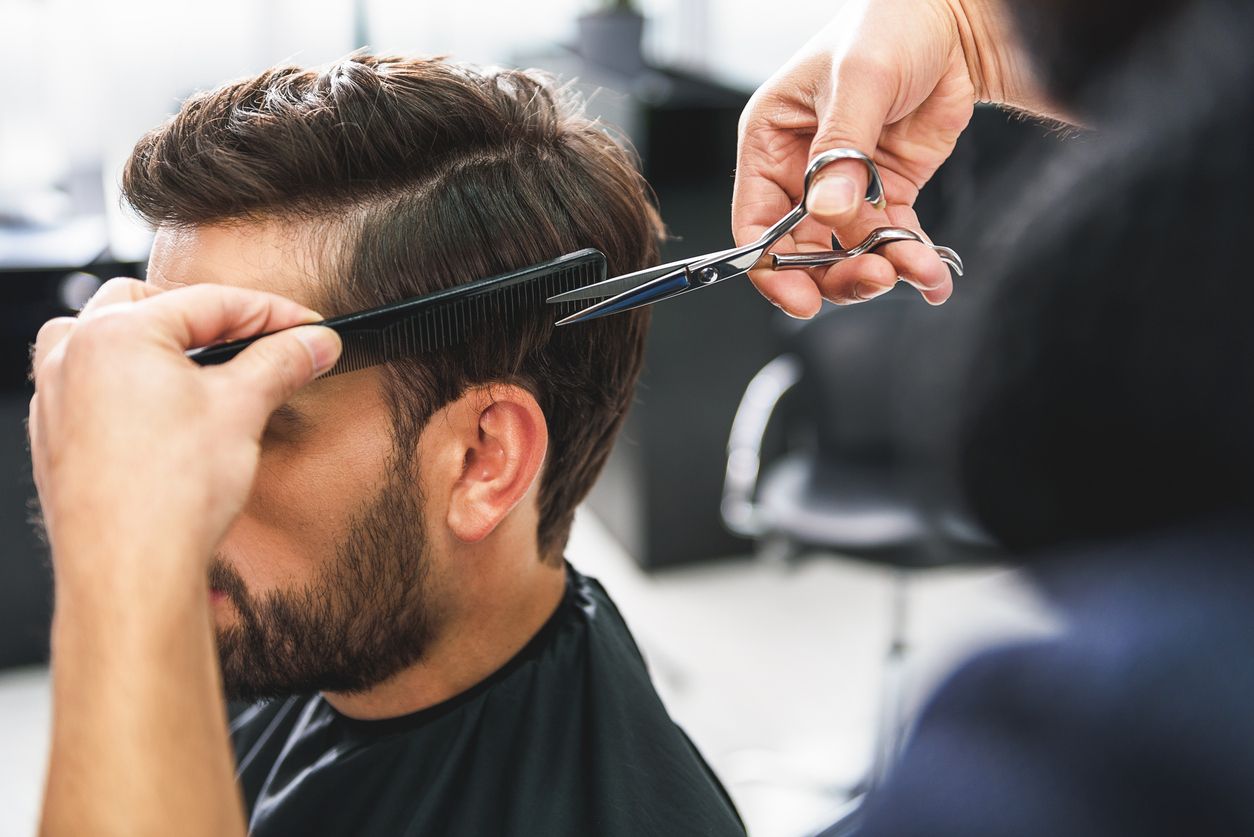 A man is getting his hair cut at a barber shop.