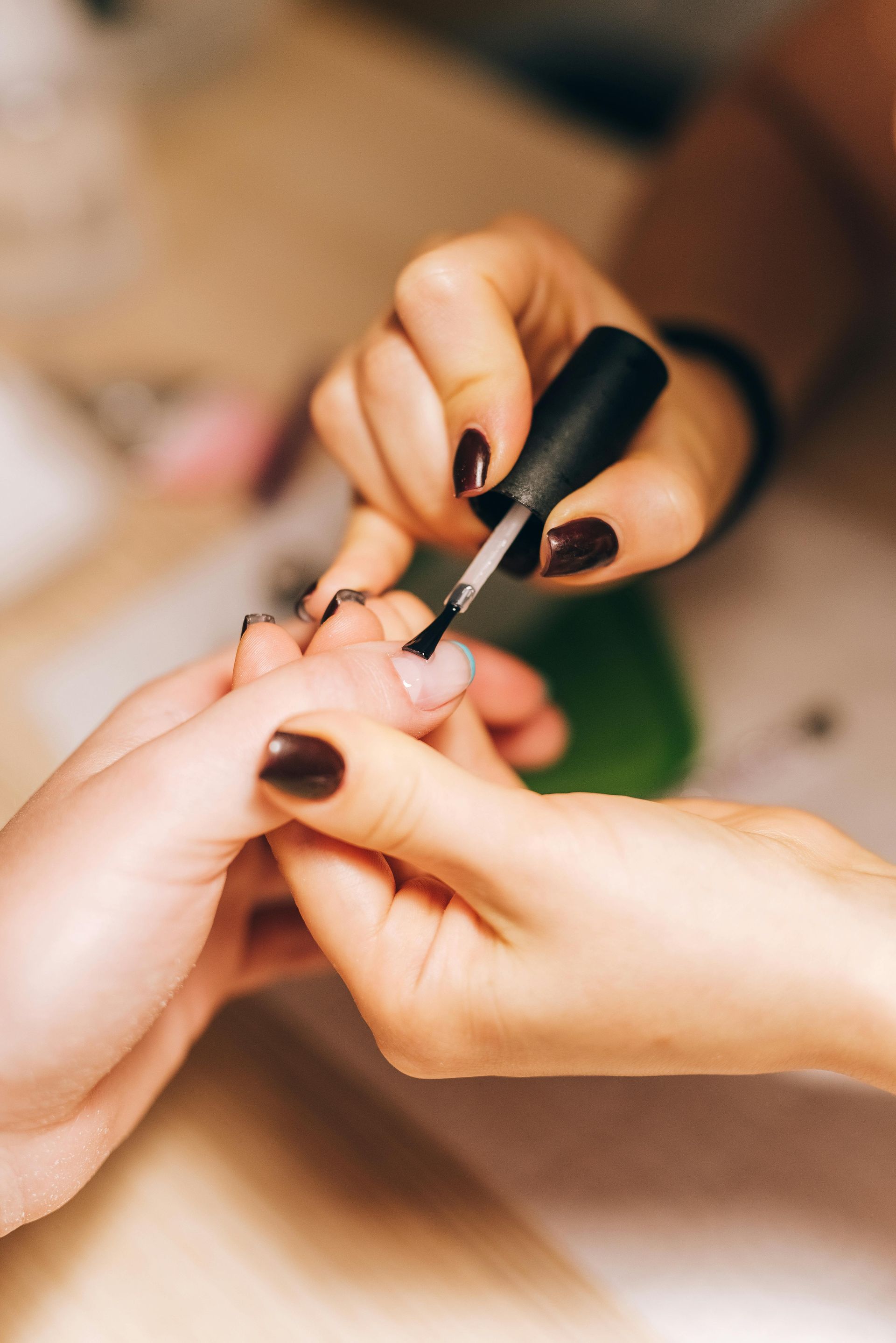 A woman is getting her nails painted by a nail artist.
