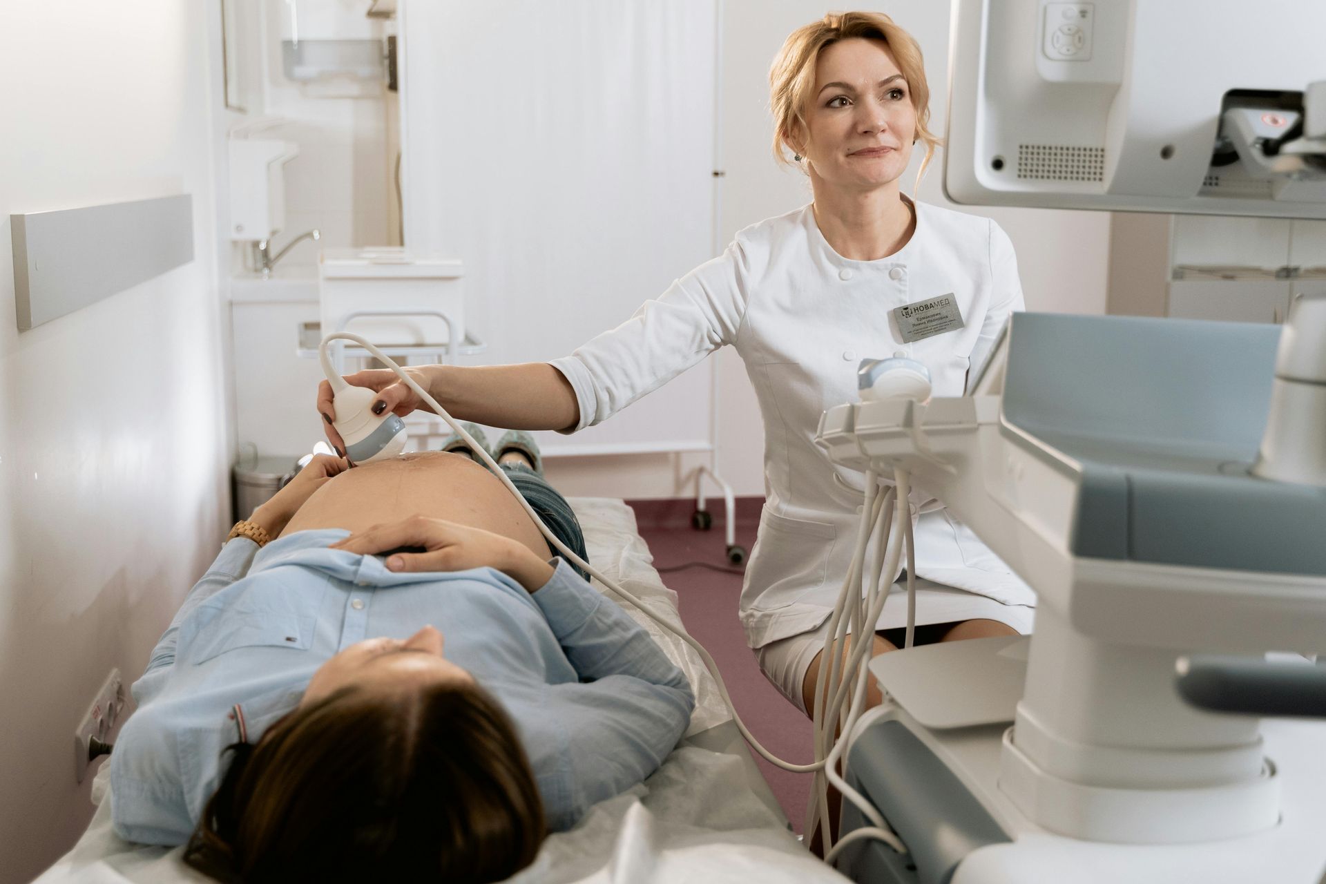 A pregnant woman is getting an ultrasound from a doctor.
