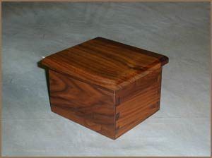 A small wooden box with a lid is sitting on a table.