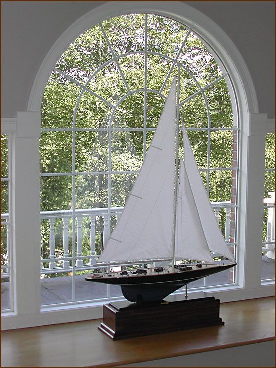 A model sailboat sits in front of a window