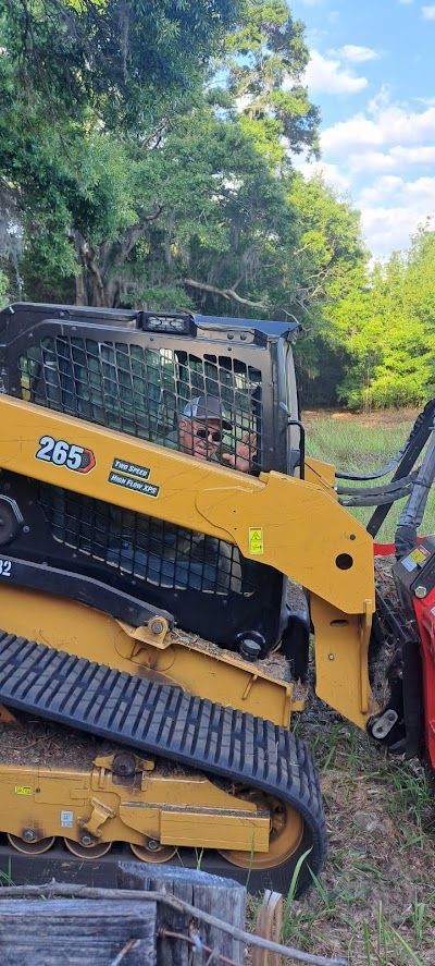 Yellow and black skid steer tractor with tracks in an outdoor setting.