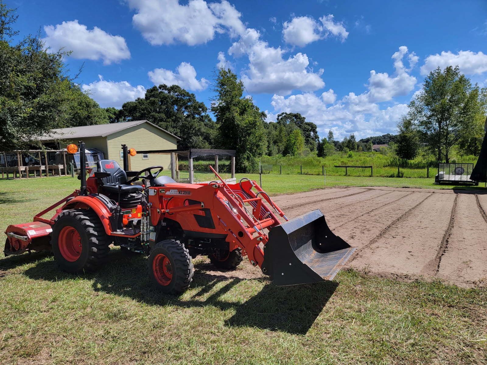 Orange tractor with a front loader on a field, sunny day.