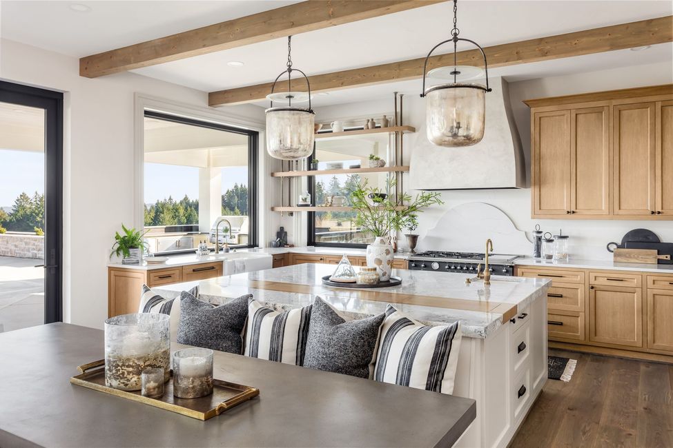Bright modern kitchen with wood cabinets, island seating, pendant lights, and large windows opening to the outdoors
