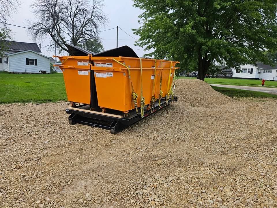 Orange construction dumpster bins on gravel pile in a residential yard