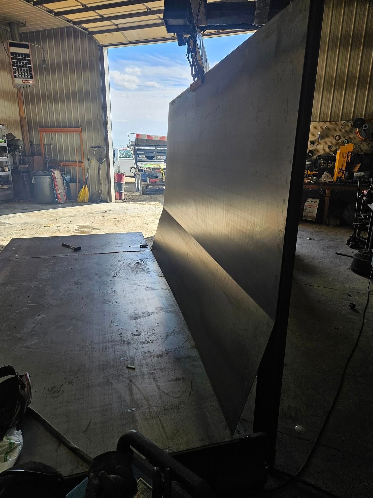 Large black metal sheet standing upright in an open workshop or warehouse doorway