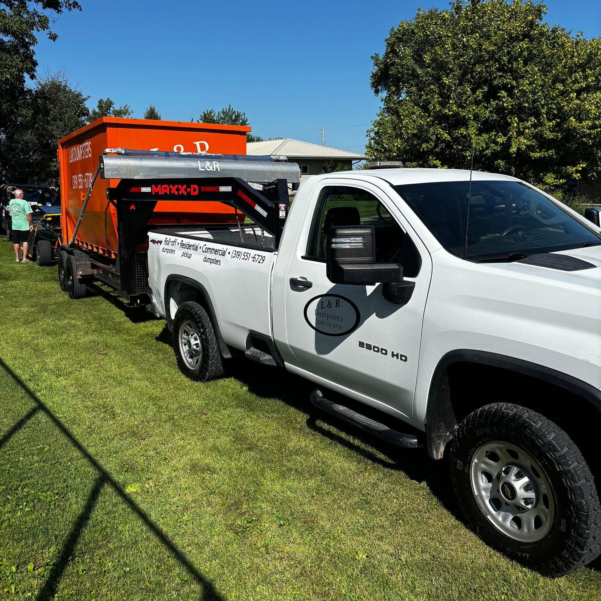 White pickup truck towing an orange trailer on grass at an outdoor event