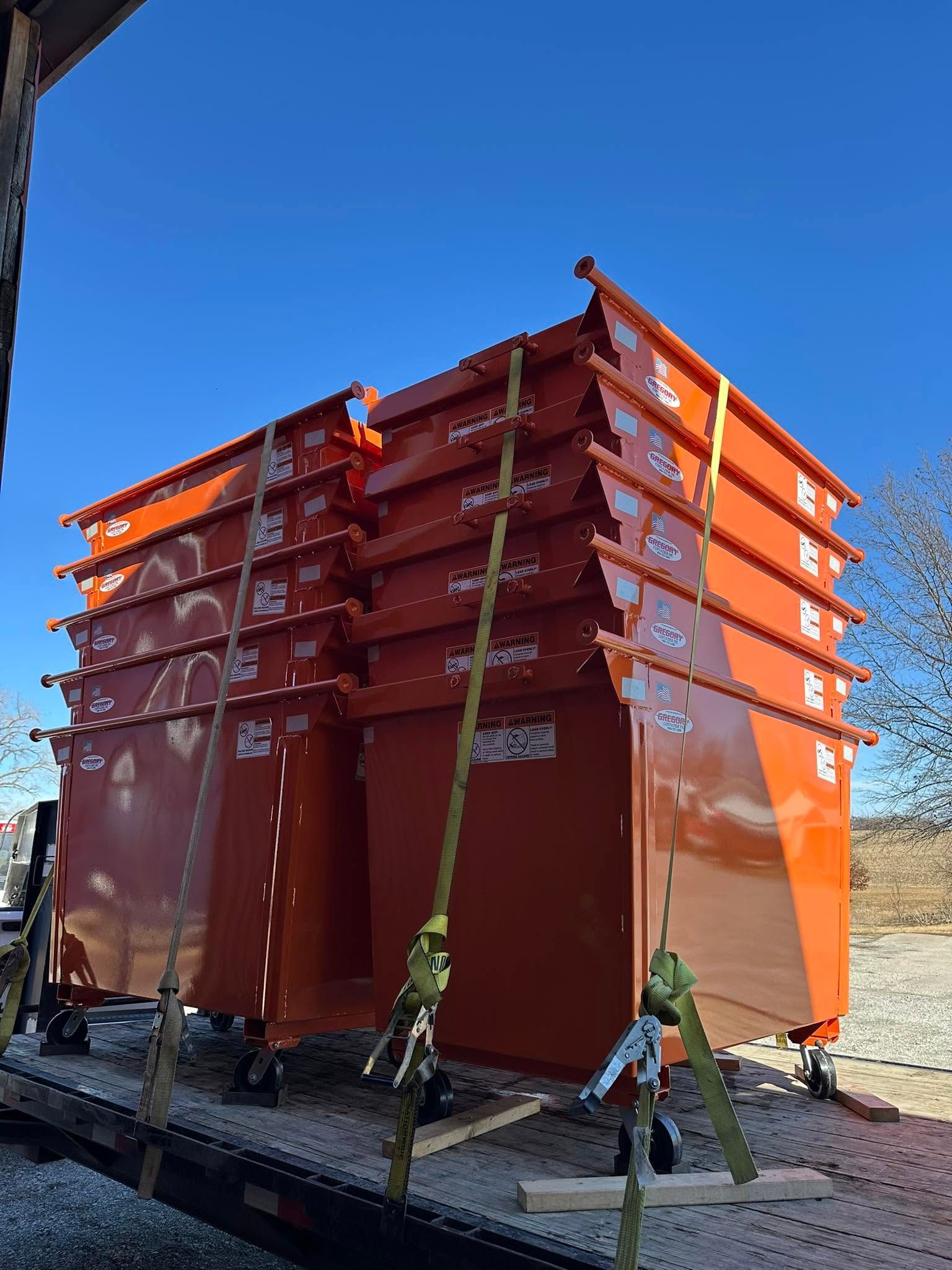 Orange industrial tank or container on a metal frame outdoors under a clear blue sky.