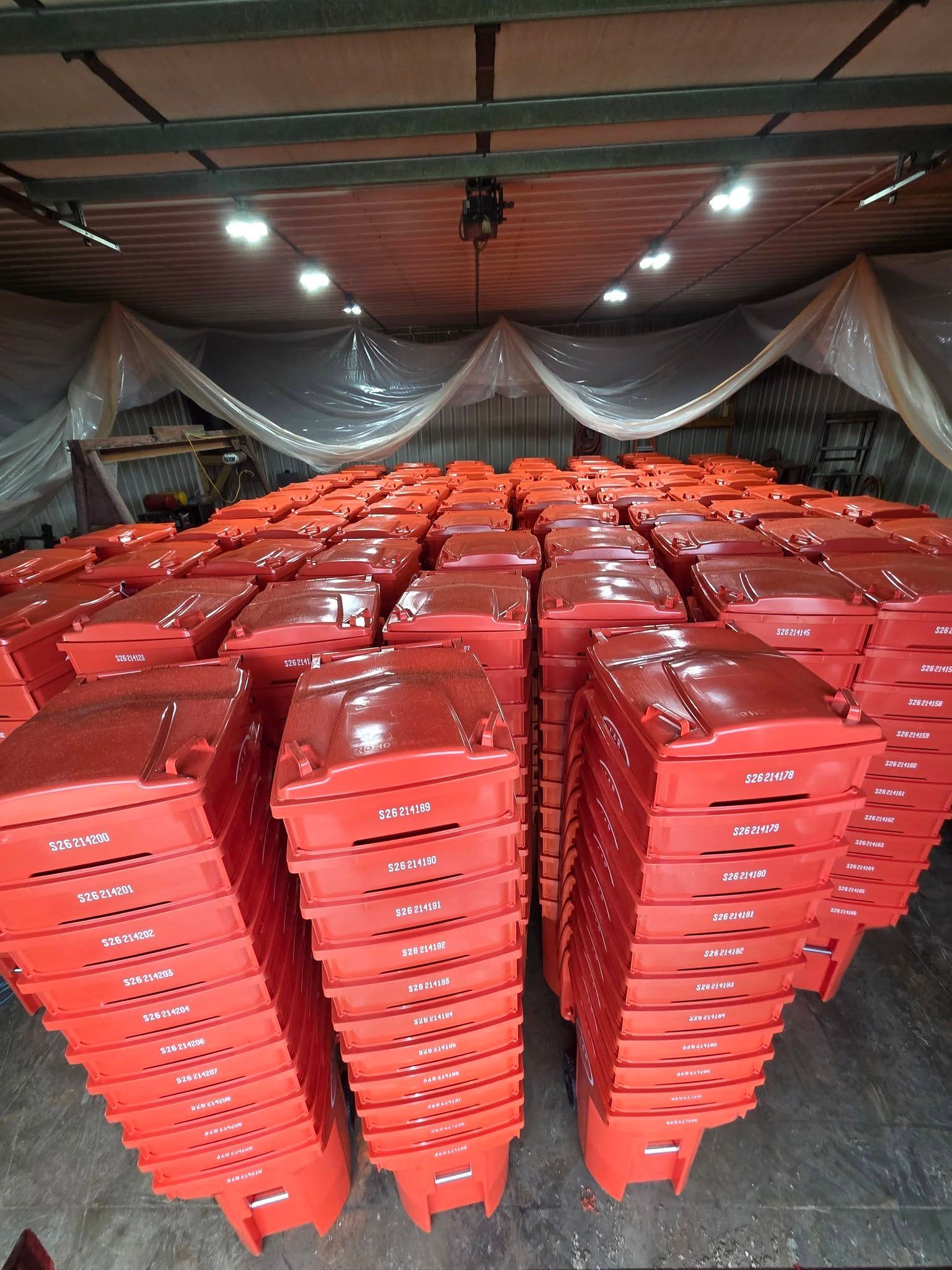 Rows of stacked red plastic chairs in a covered indoor hall